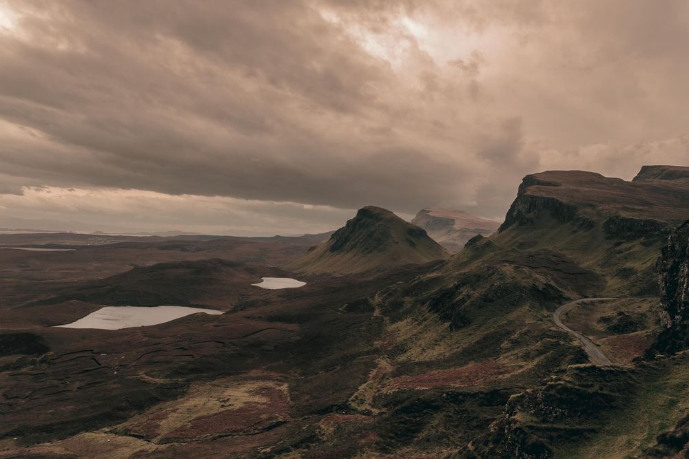 Dramatic landscape of the Quiraing on Isle of Skye with moody clouds and small lakes dotting the rugged Scottish terrain.
