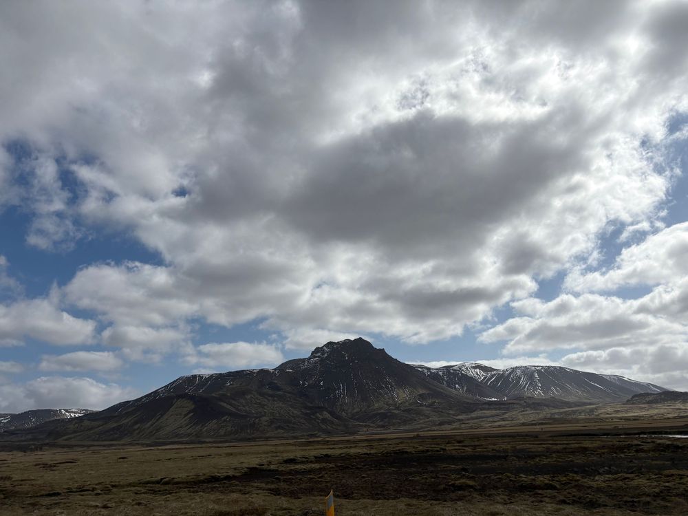Dramatic cloudy sky over rugged mountain peak and barren landscape in rural mountainous terrain.