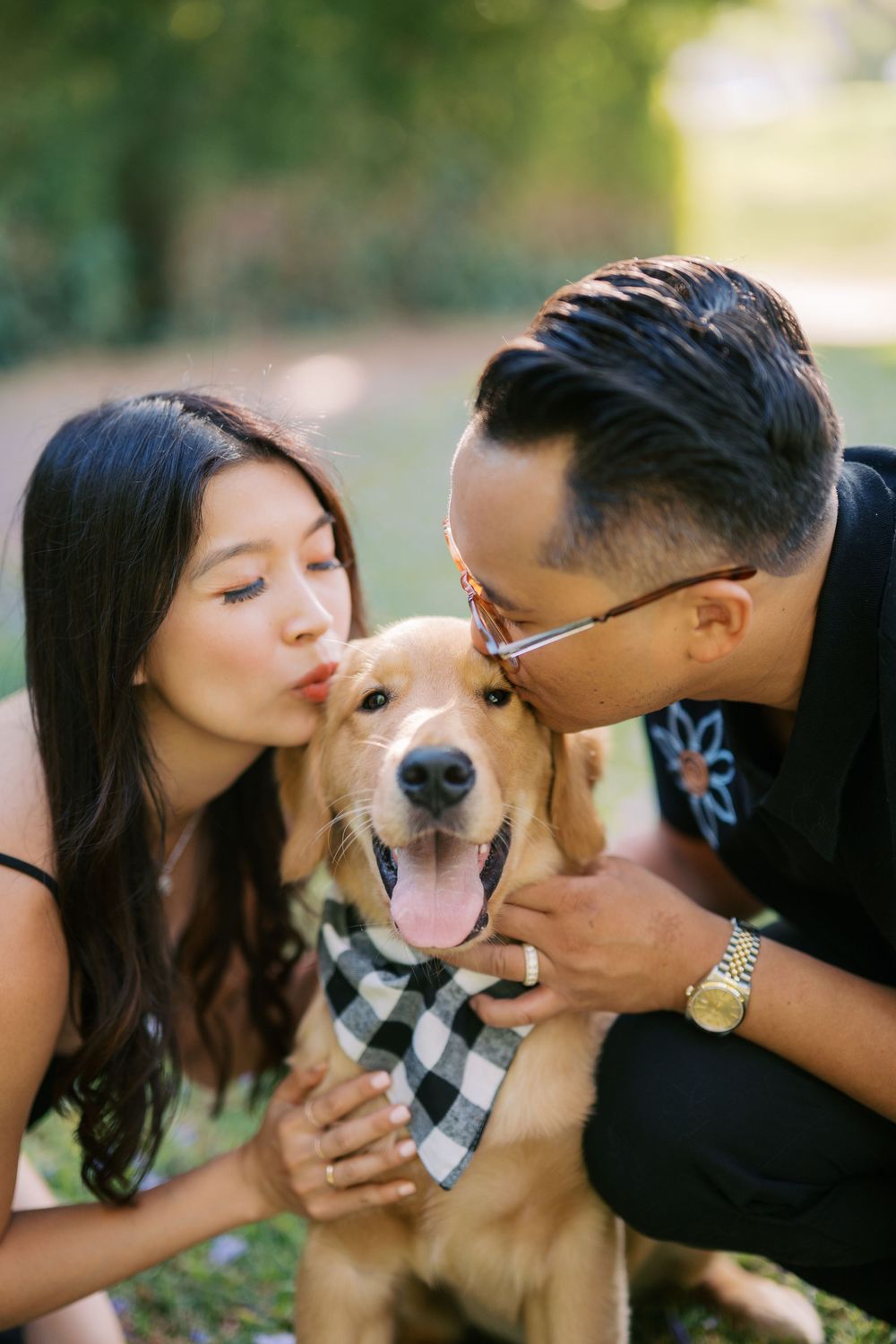 A couple shares loving kisses with their golden retriever wearing a checkered bandana in a series of outdoor photos.