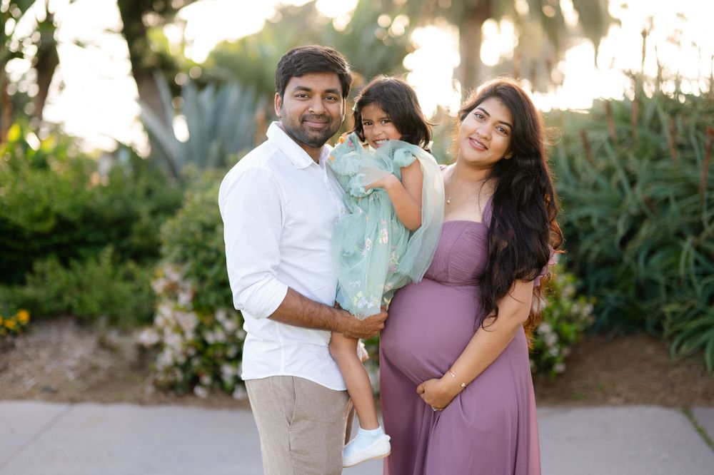 Family portrait in garden setting with lush greenery during golden hour.
