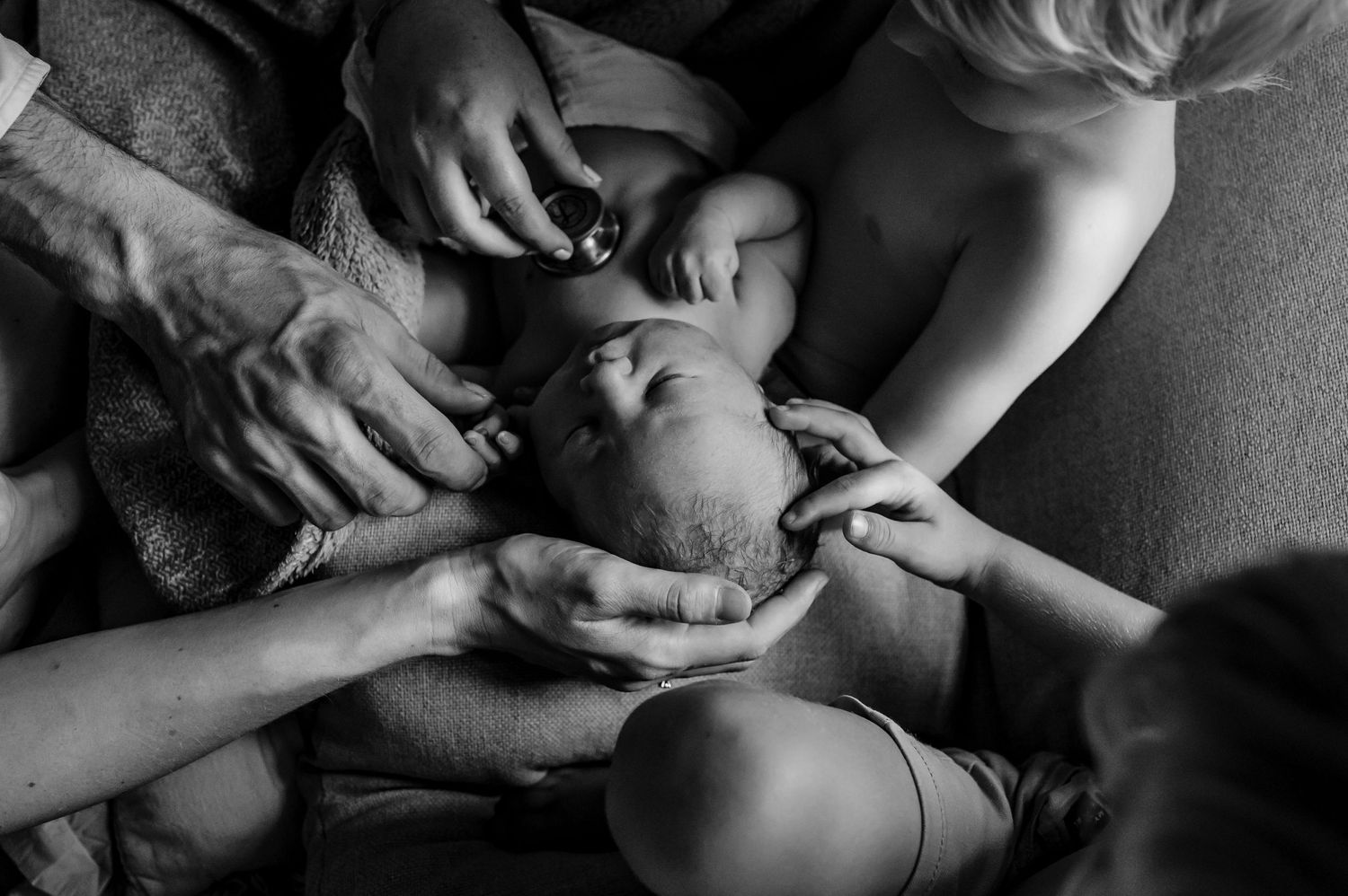 Black and white intimate portrait of hands cradling a newborn.