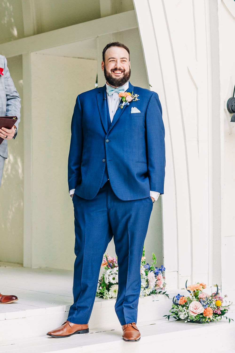A formal wedding photo showing navy blue suits and brown dress shoes against white architectural columns.