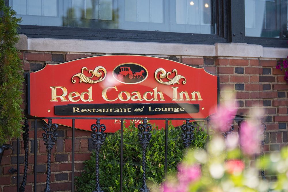 Red Coach Inn restaurant and lounge sign with pink flowers in foreground.