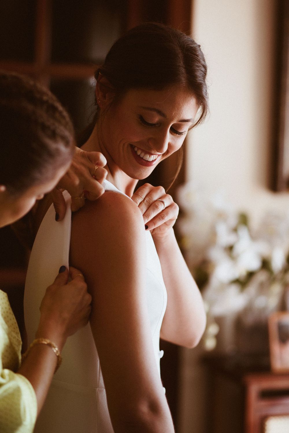 A candid moment shows the final touches of wedding preparation in soft lighting.