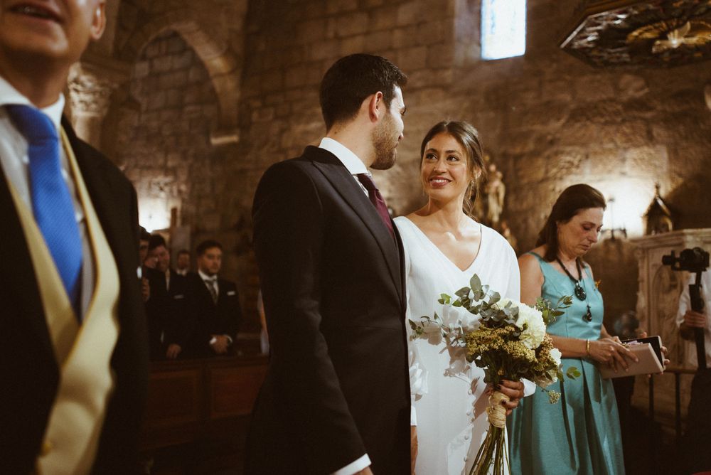 Wedding ceremony in progress inside historic stone church with vaulted ceilings.