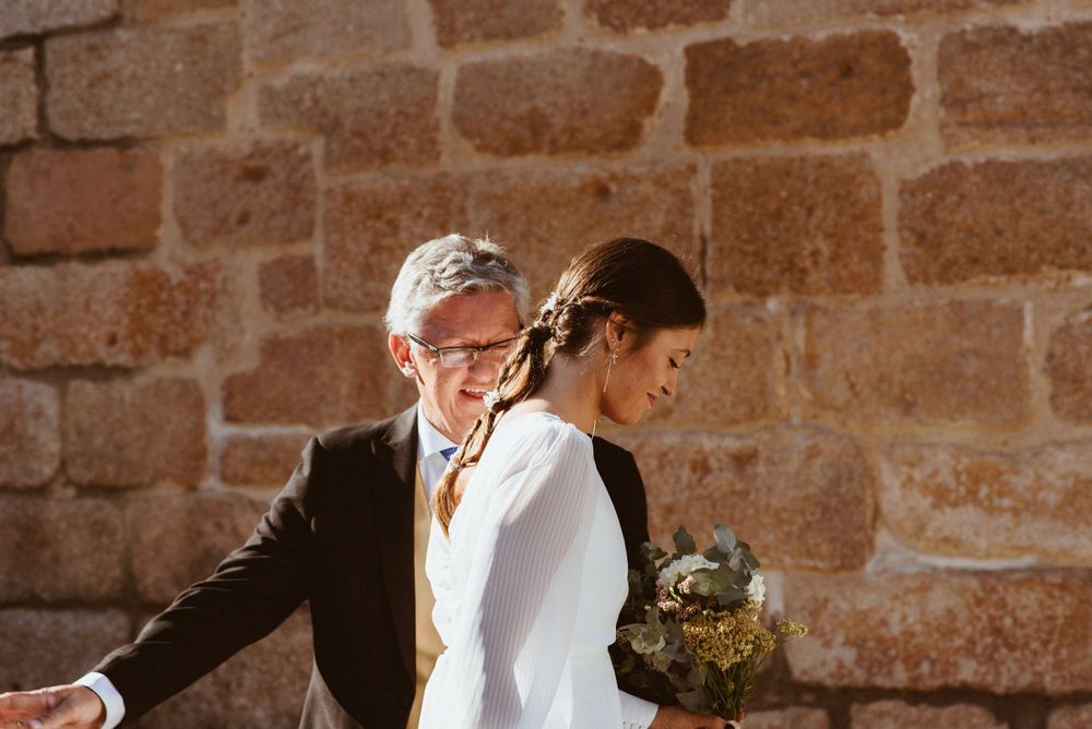 Wedding couple walking together through historic stone church hallway.