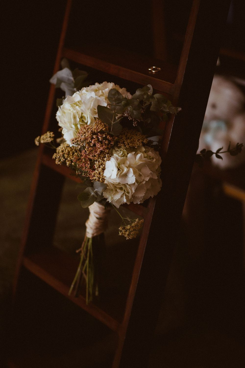 A delicate white and cream floral bouquet rests against a dark wooden frame.