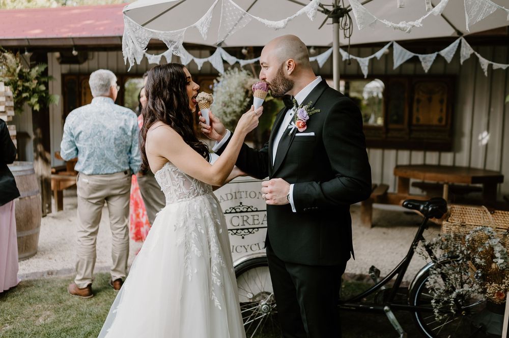 A couple shares a tender moment while dancing at an outdoor wedding reception under white tent decorations.