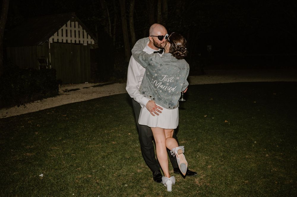 A couple embraces on a lawn at night, with the bride wearing a short dress.