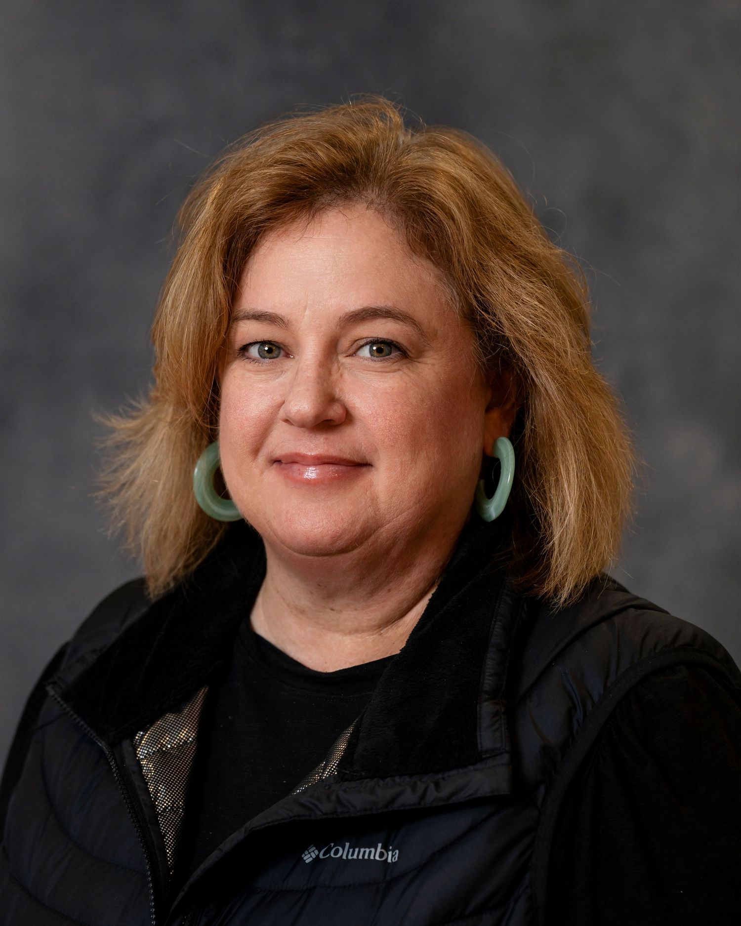 Professional headshot portraits of someone in a black jacket against a dark gray studio backdrop.