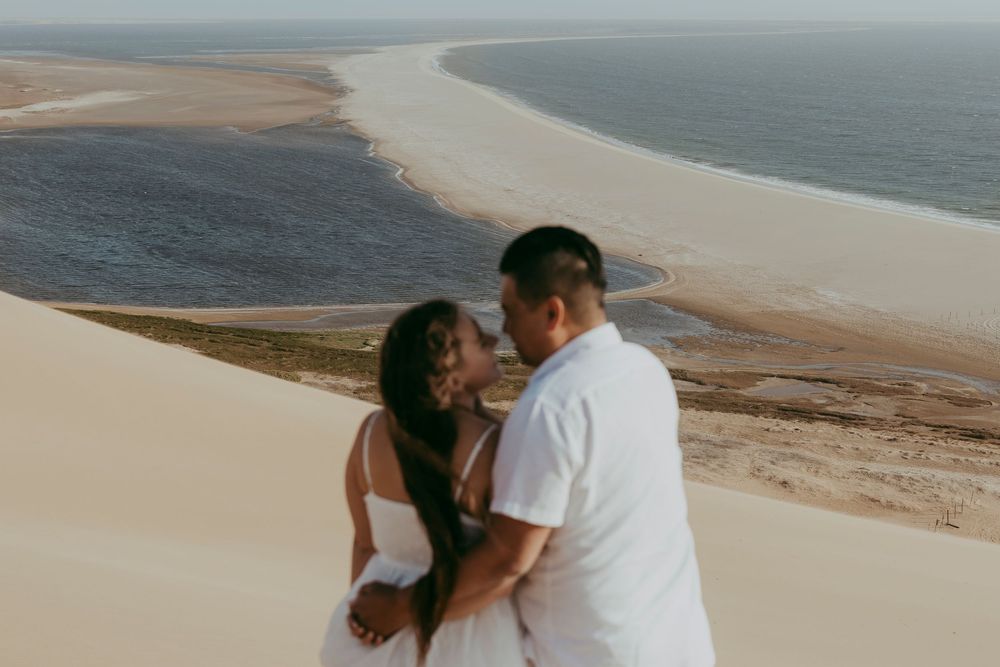 A surprise proposal unfolding on top of a dune in Sandwich Harbour, with the woman reacting emotionally as the sun sets behind them.