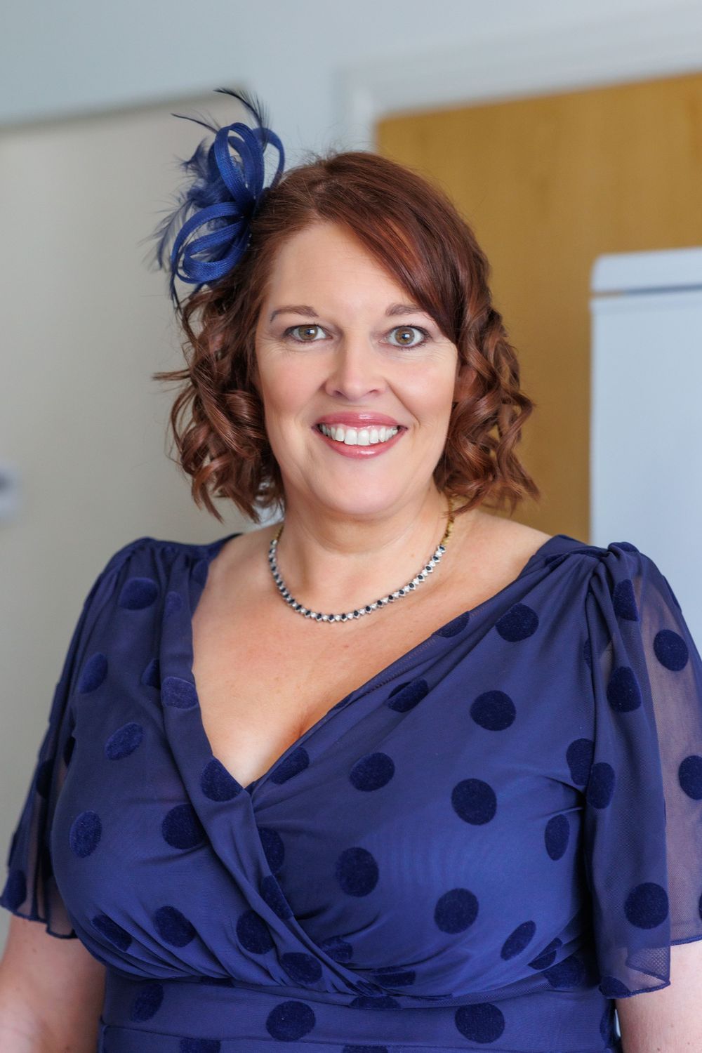 Woman in a navy polka dot dress with flutter sleeves smiling at different angles.