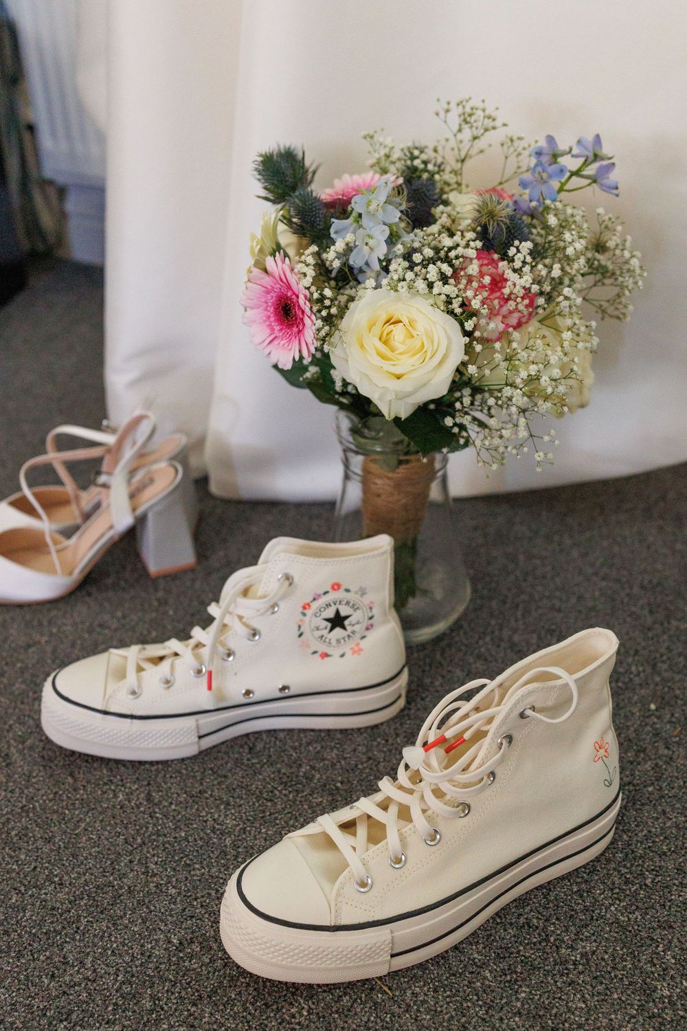 White Converse sneakers with floral arrangements displayed in a wedding setting.