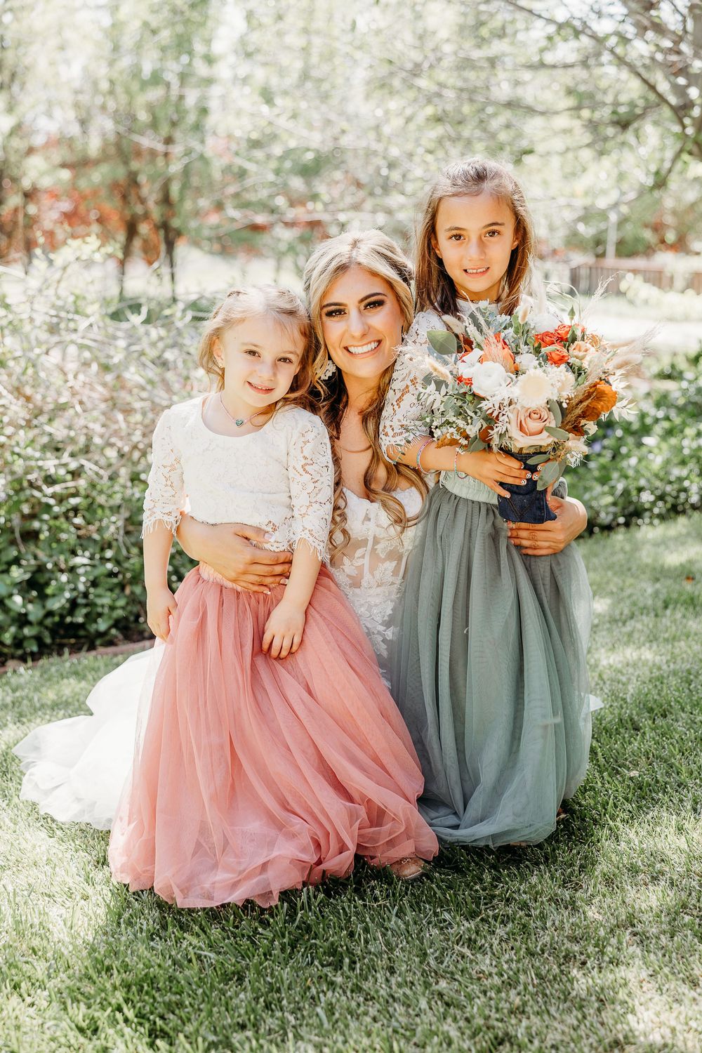Beautiful spring wedding portrait with floral bouquets and flowing pastel dresses.