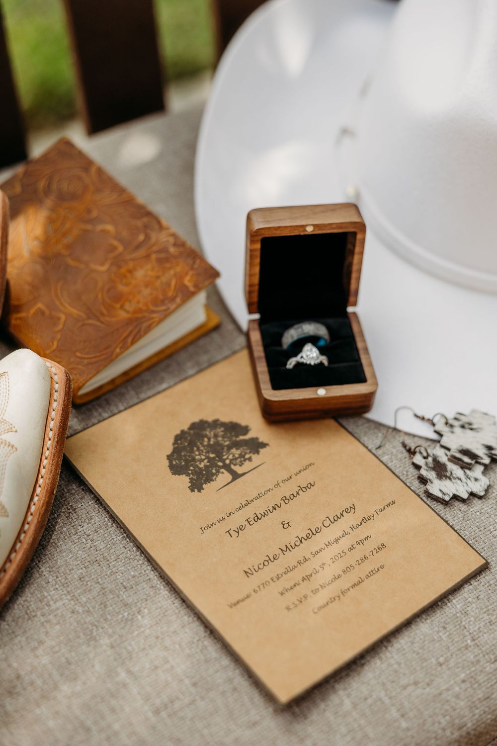 Wedding invitation and engagement ring in wooden box displayed with vintage books.