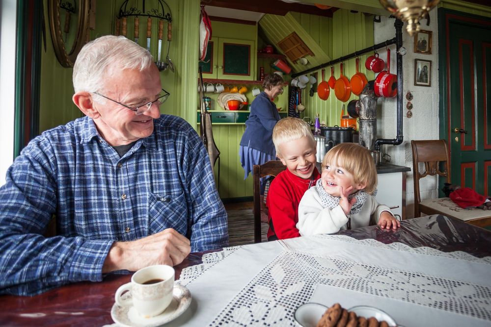 Family members enjoy quality time together at a dining table with coffee and festive holiday decor in the background.