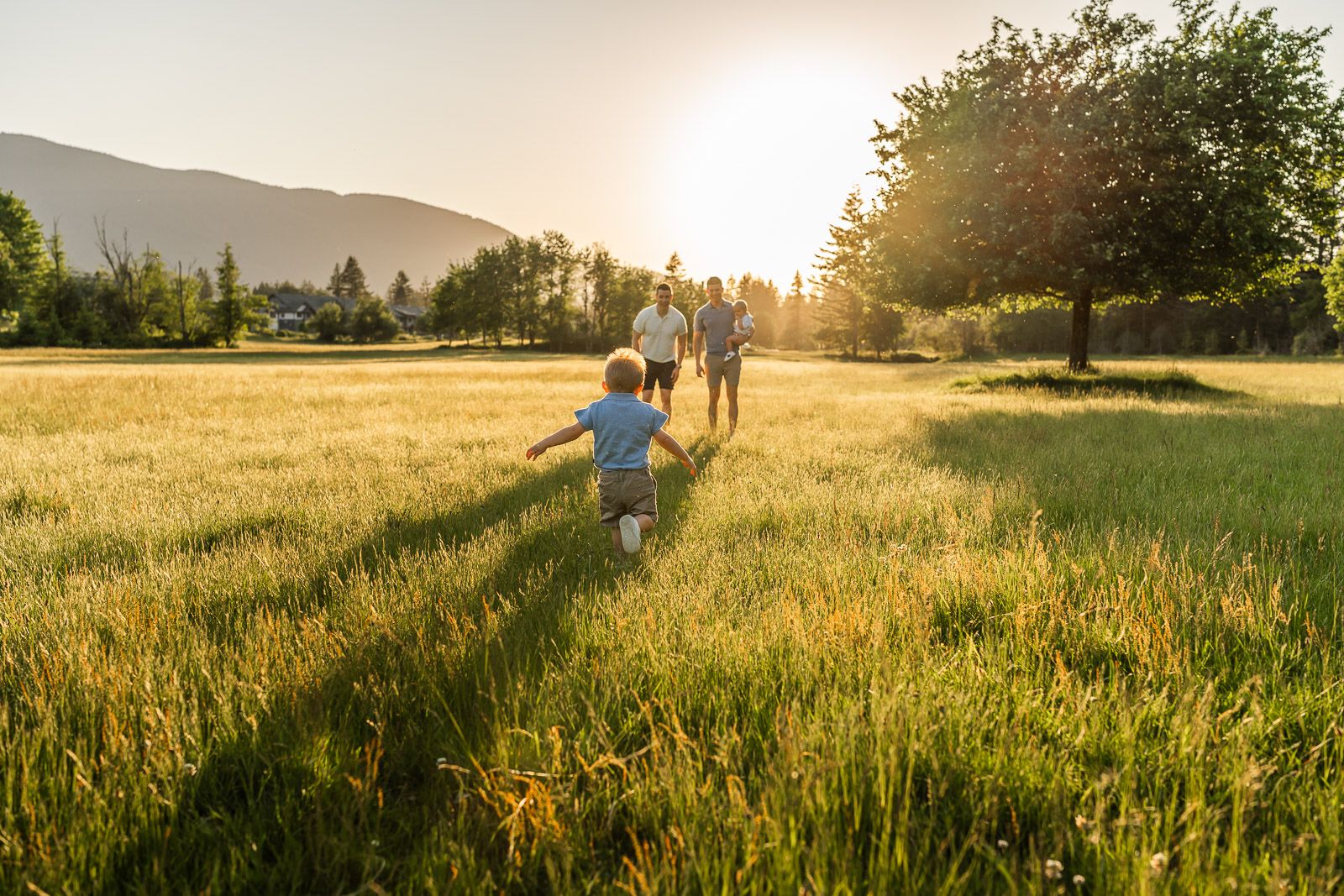 Child running towards his dads at Tanner Landing park in sunset.