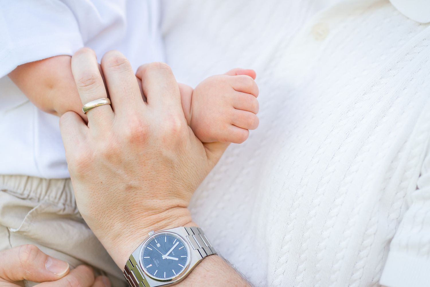 Detail photo of dad holding baby's hand.