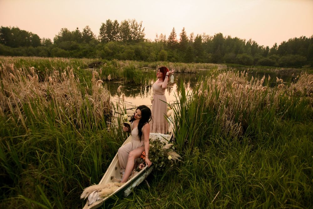Couple resting on vintage bed surrounded by serene meadow grasses at golden hour.