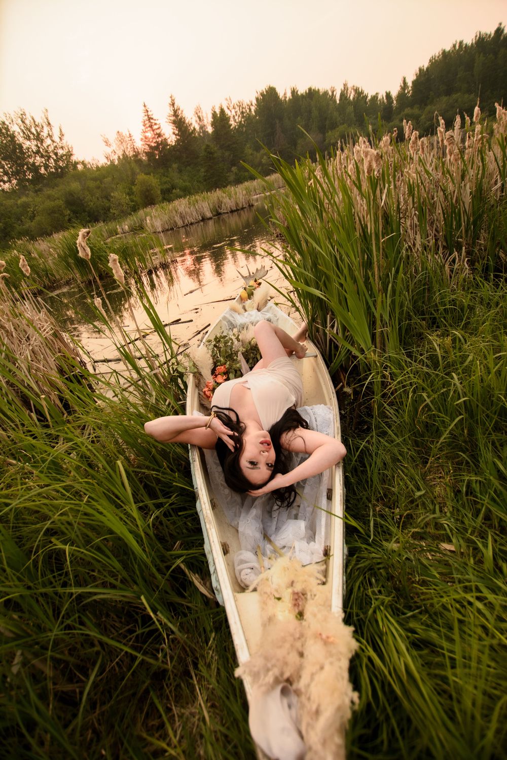 White vintage bathtub with rippling water surrounded by cattails and marsh grass at dusk.