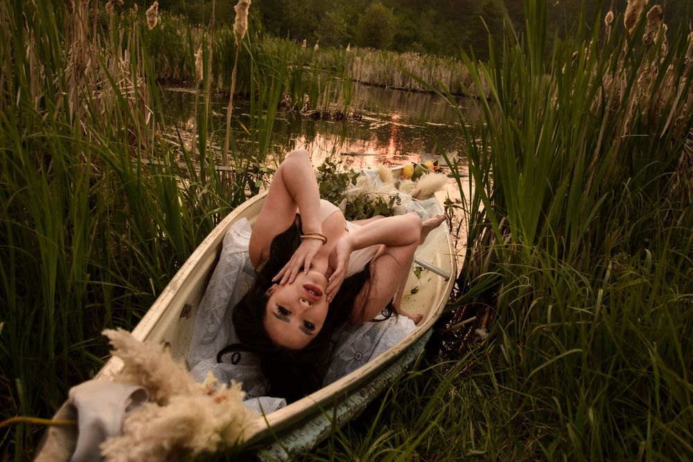 Sequence of dramatic fashion photographs showing a model lying in tall grass at sunset wearing a white dress.