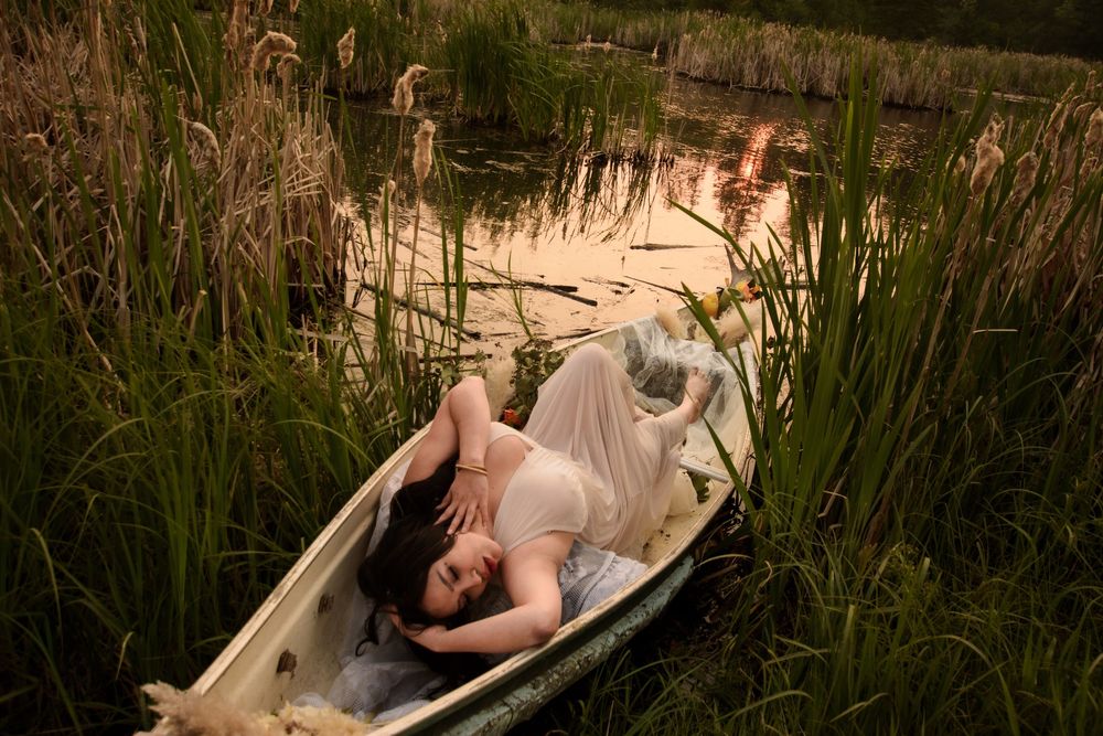 Old clawfoot tub positioned in marshland with golden sunset light filtering through trees.