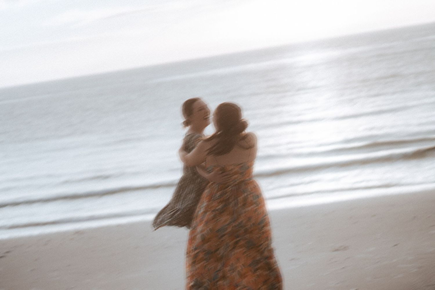 A loving couple embraces on the beach during sunset as the incoming waves gently wash over their feet.