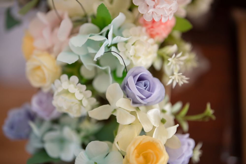 A delicate floral arrangement featuring pastel roses in purple, yellow and peach with soft green foliage. Juliette Chapel Wedding photos