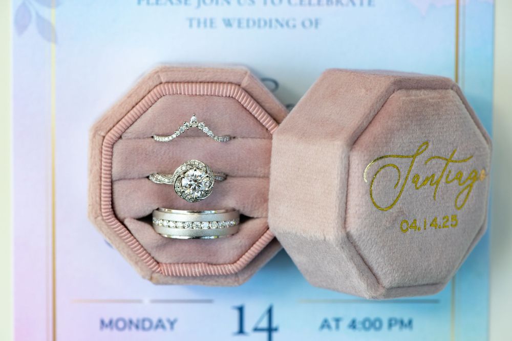 Elegant engagement ring and wedding band set displayed in a pink velvet octagonal ring box with gold lettering. Juliette Chapel Wedding phot