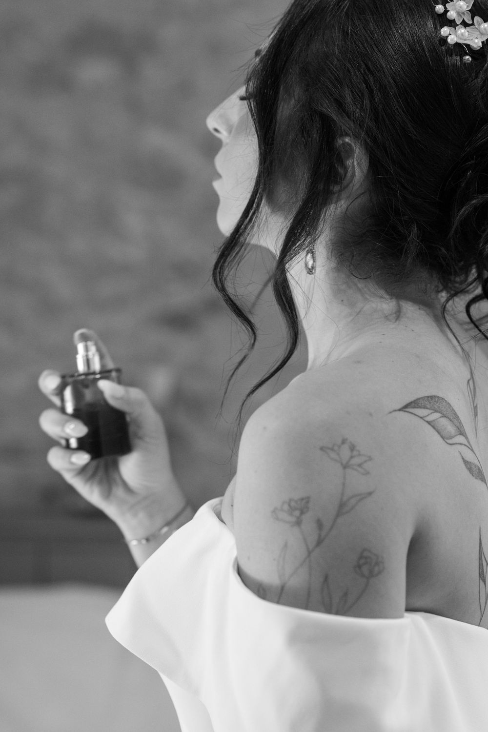 La mariée qui se parfume légèrement lors de la fin de la préparation dans la chambre du domaine