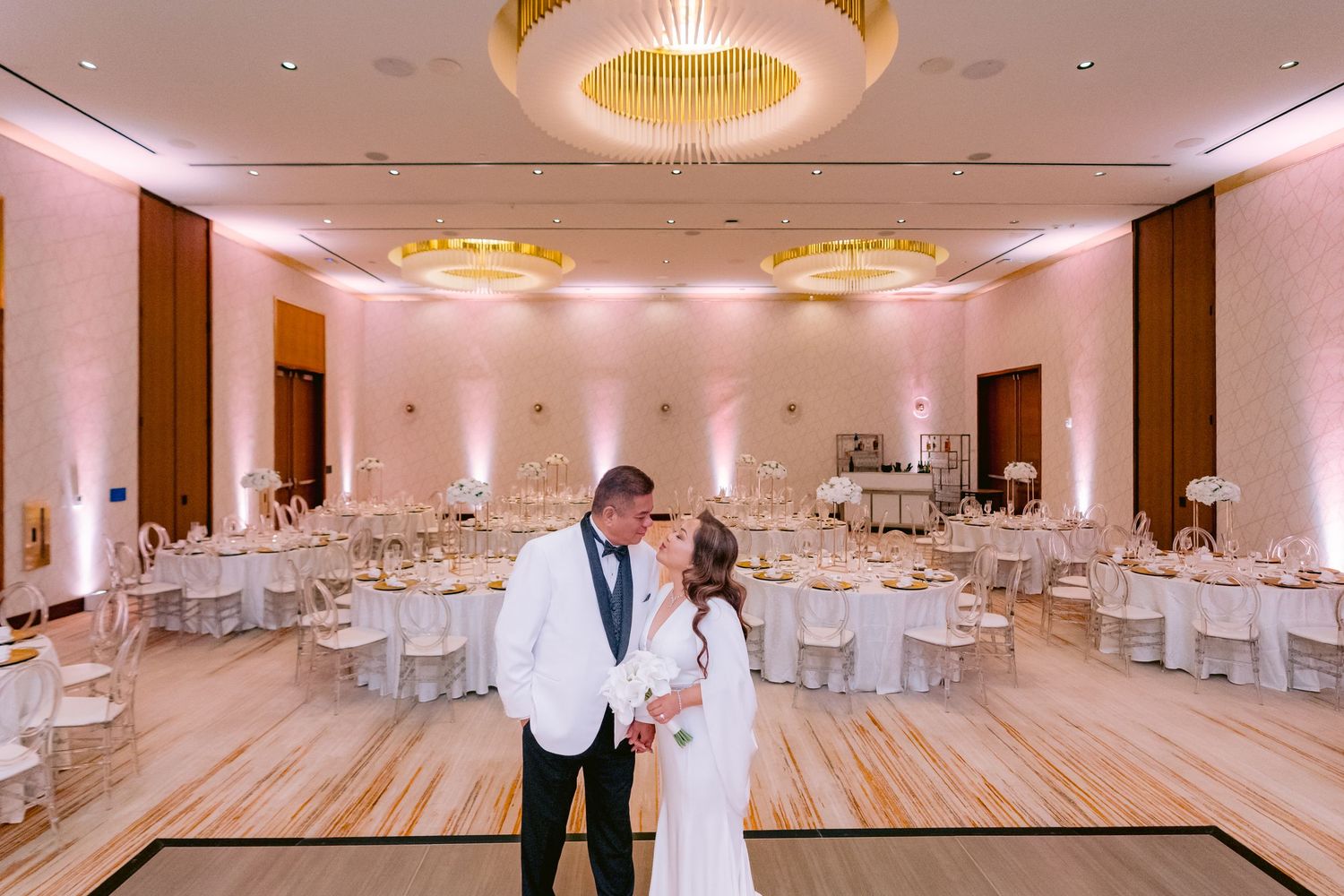 Elegant ballroom setup with white round tables and golden circular chandeliers at Lake Nona Wave Hotel.