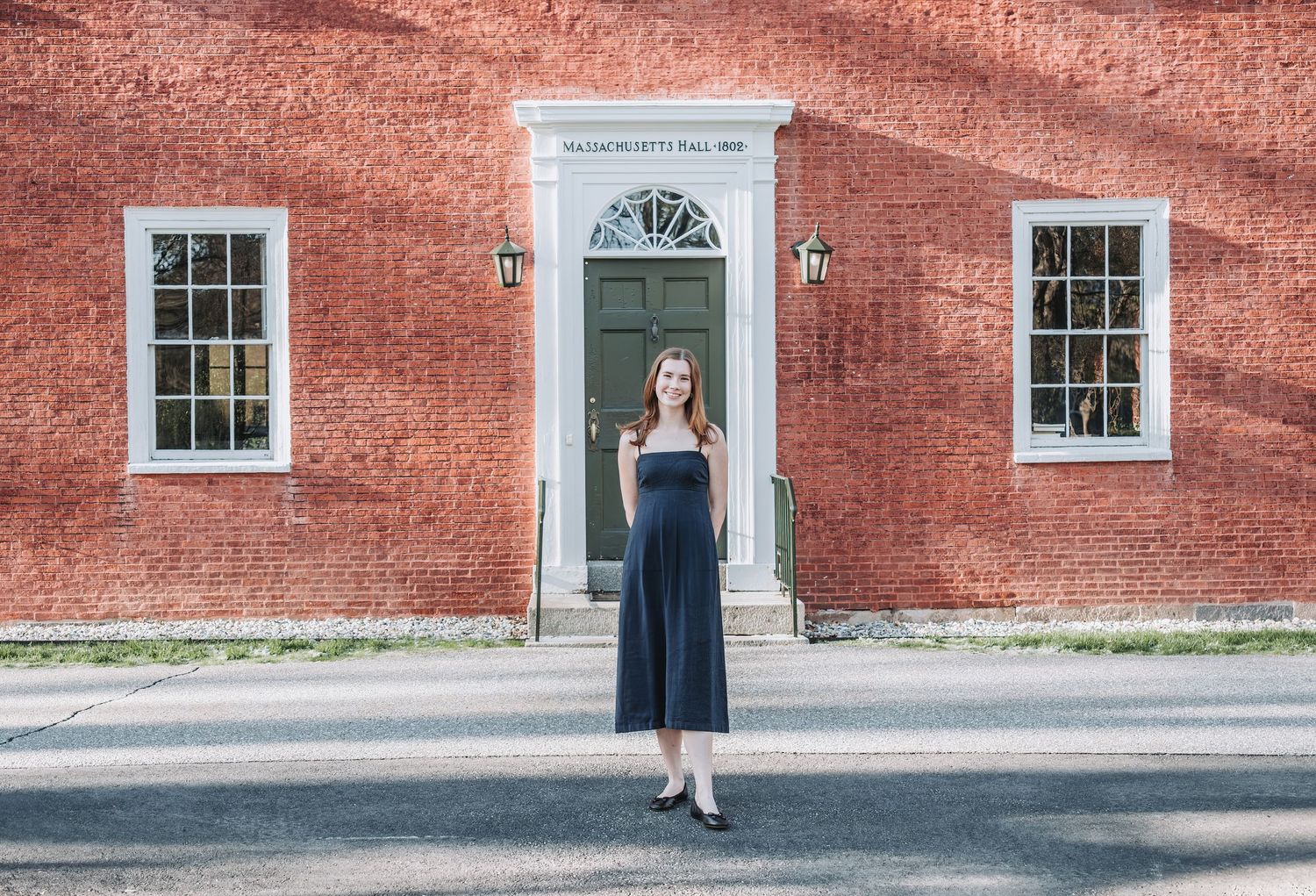 An old, red brick building with a Georgian doorway and windows provides an elegant backdrop for a senior photo session at Bowdoin College.