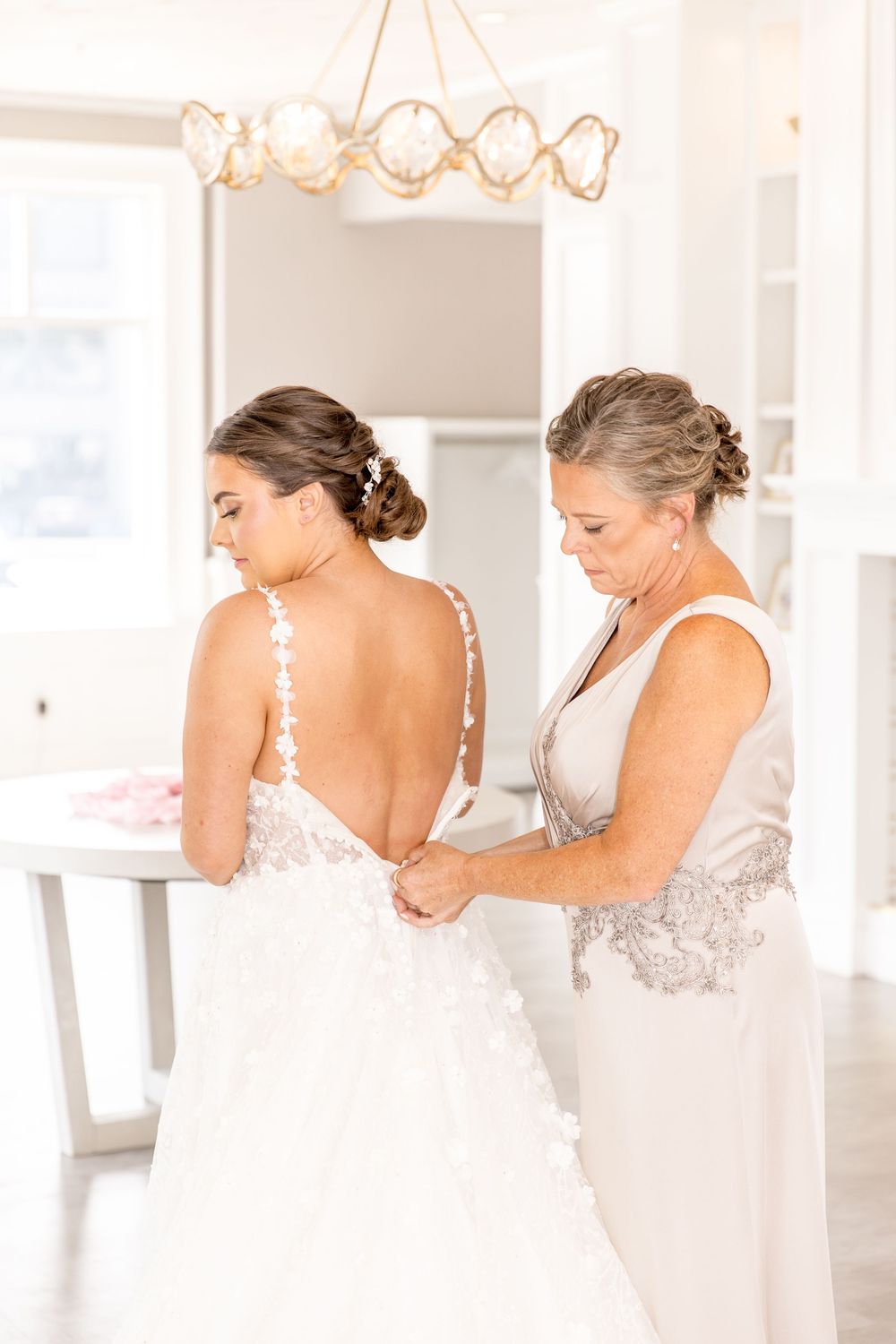 A heartwarming moment captured in a bright white room as wedding preparations are underway.