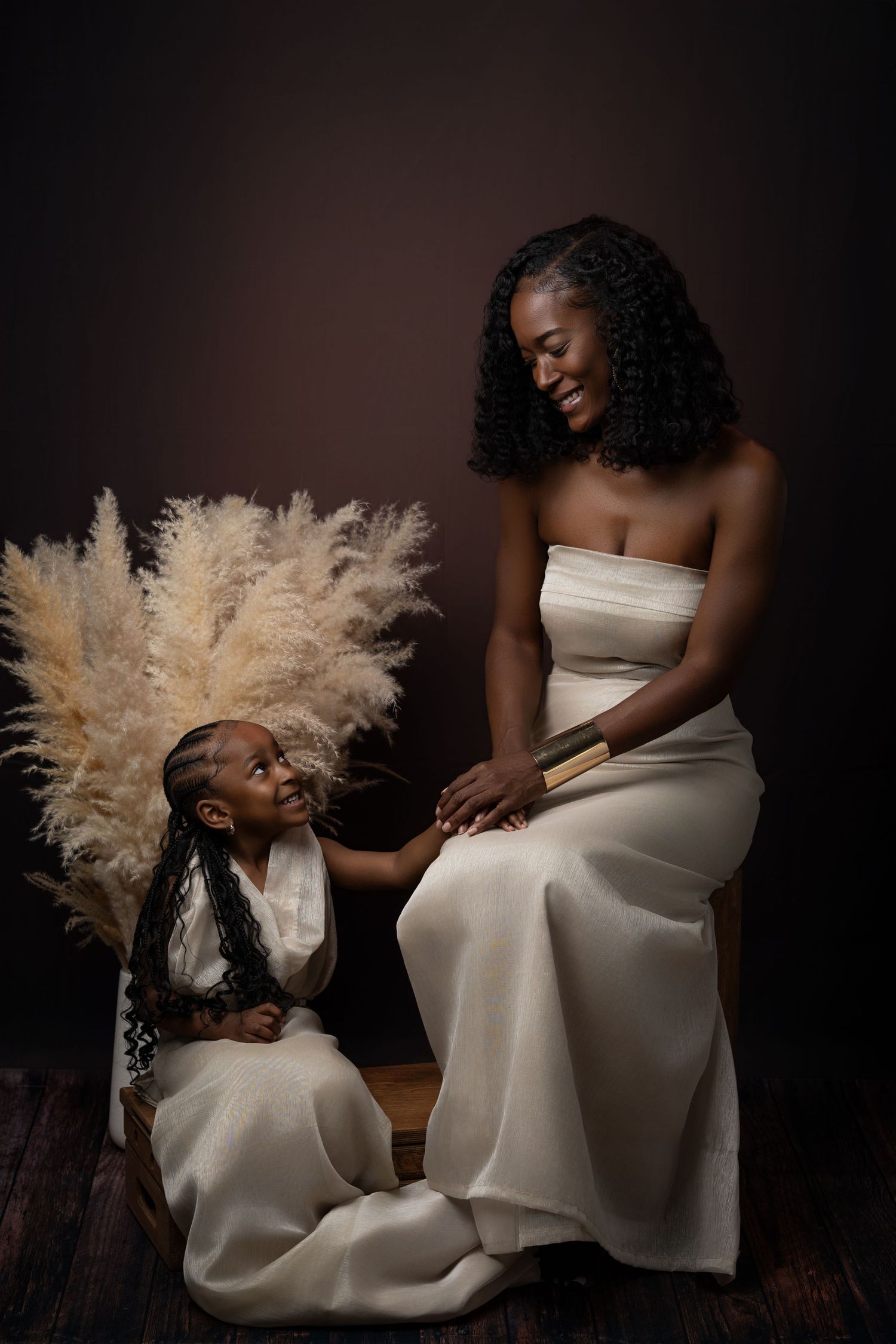 A series of artistic portraits showing two people in elegant white dresses with dried pampas grass accents against a dark background.