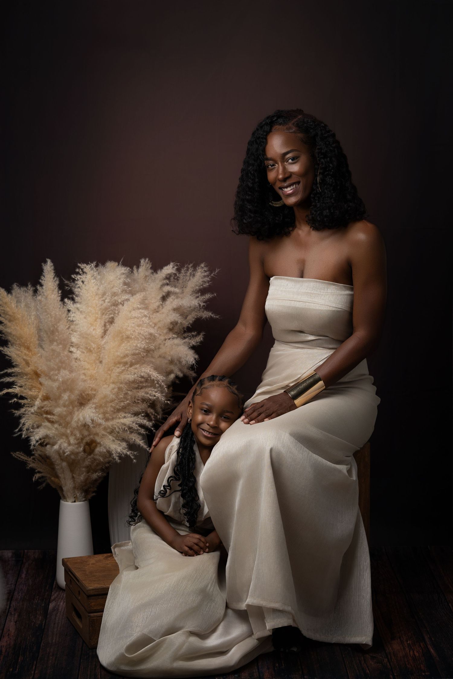 A woman in a white dress sits with delicate pampas grass decoration creating an elegant artistic portrait series.