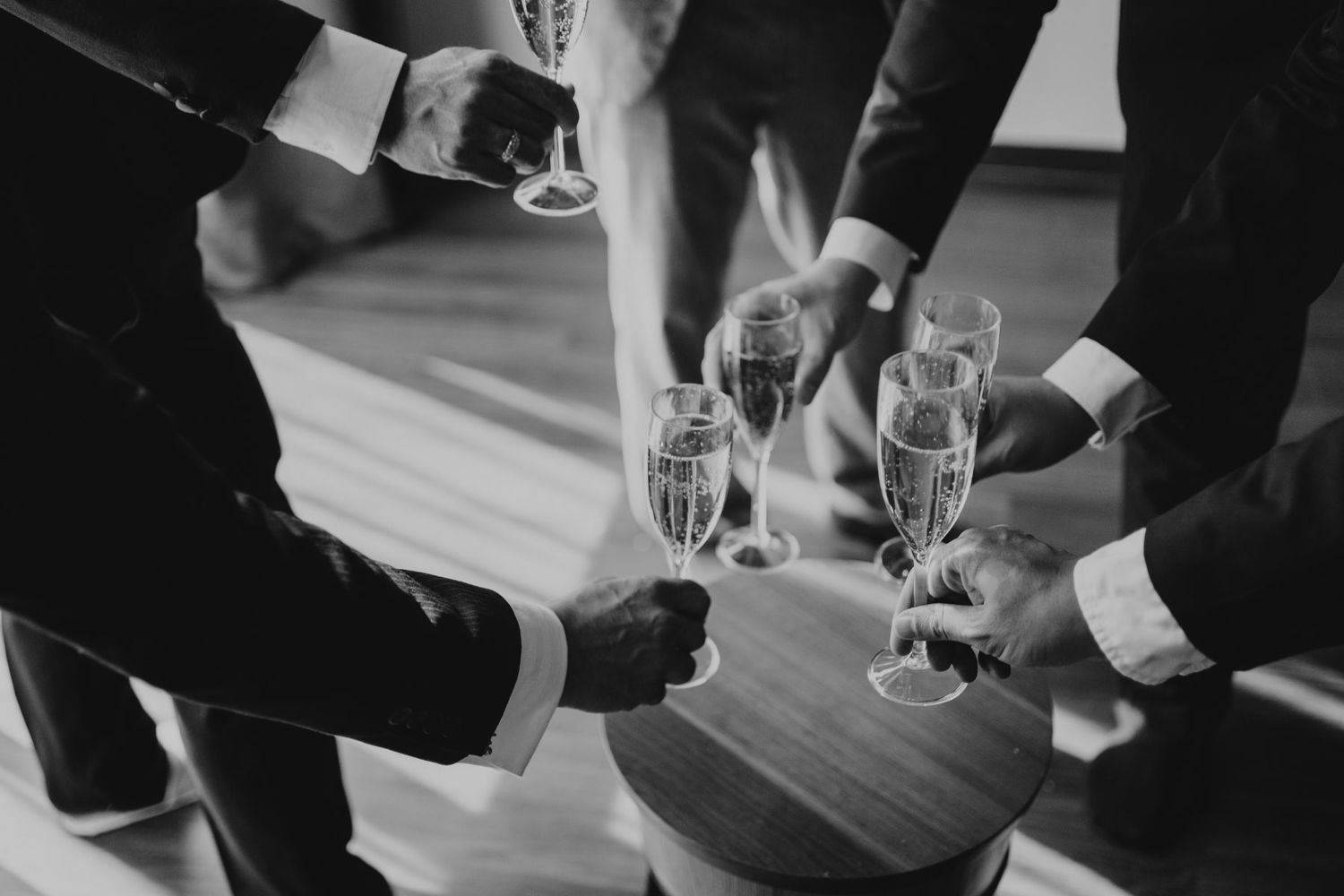 People's hands clinking wine glasses in a celebratory toast at a formal gathering.