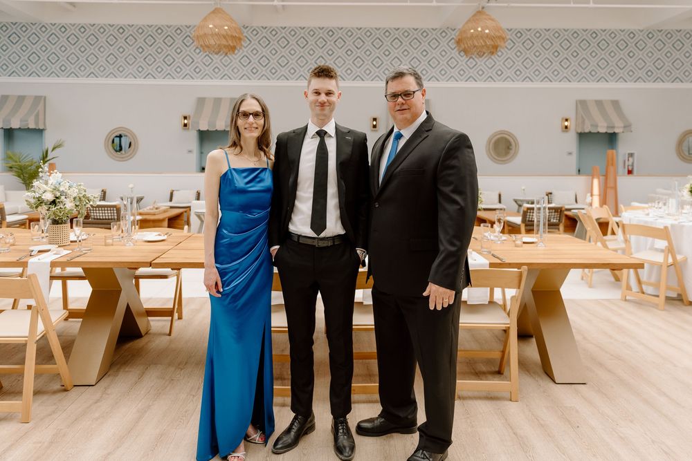 A wedding party in classic black suits and royal blue dresses poses together in an elegant reception venue.