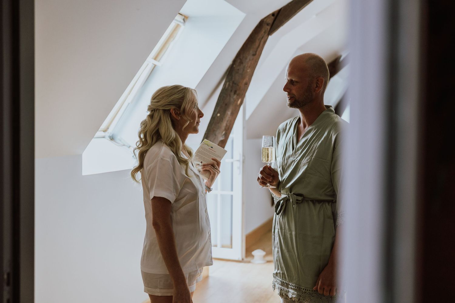 Two people having an animated discussion while standing in a bright room with a skylight window.