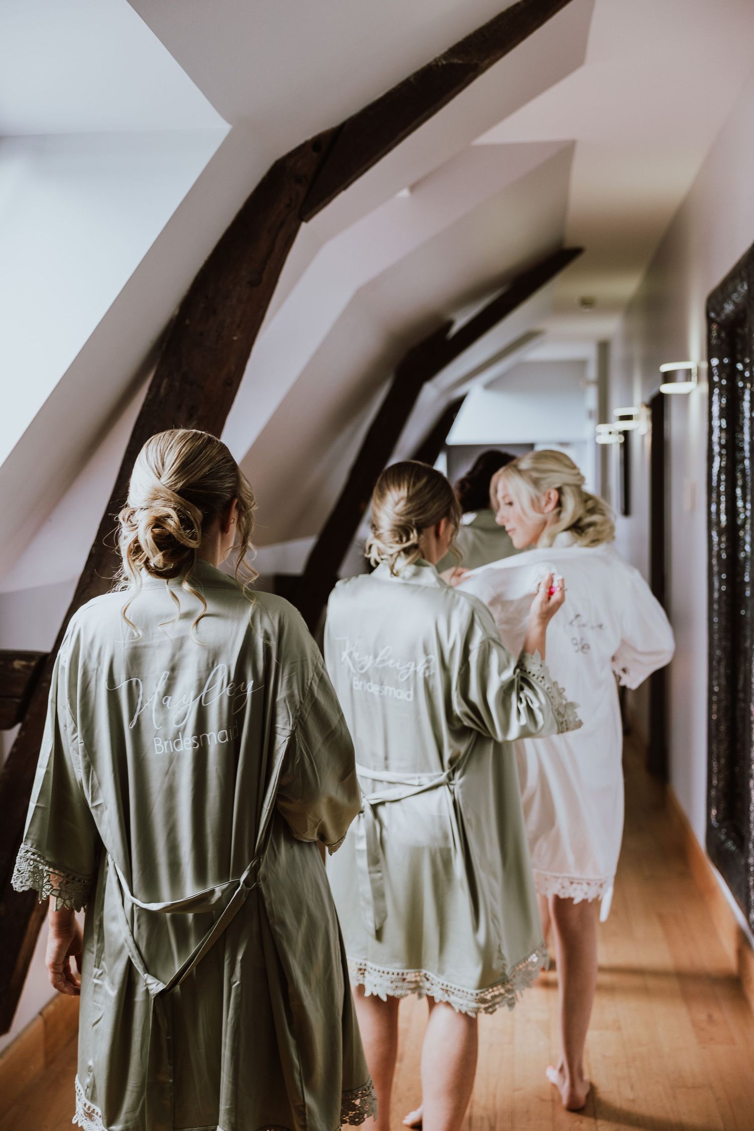 People wearing white and gray robes walk down a hallway on a sunny morning.