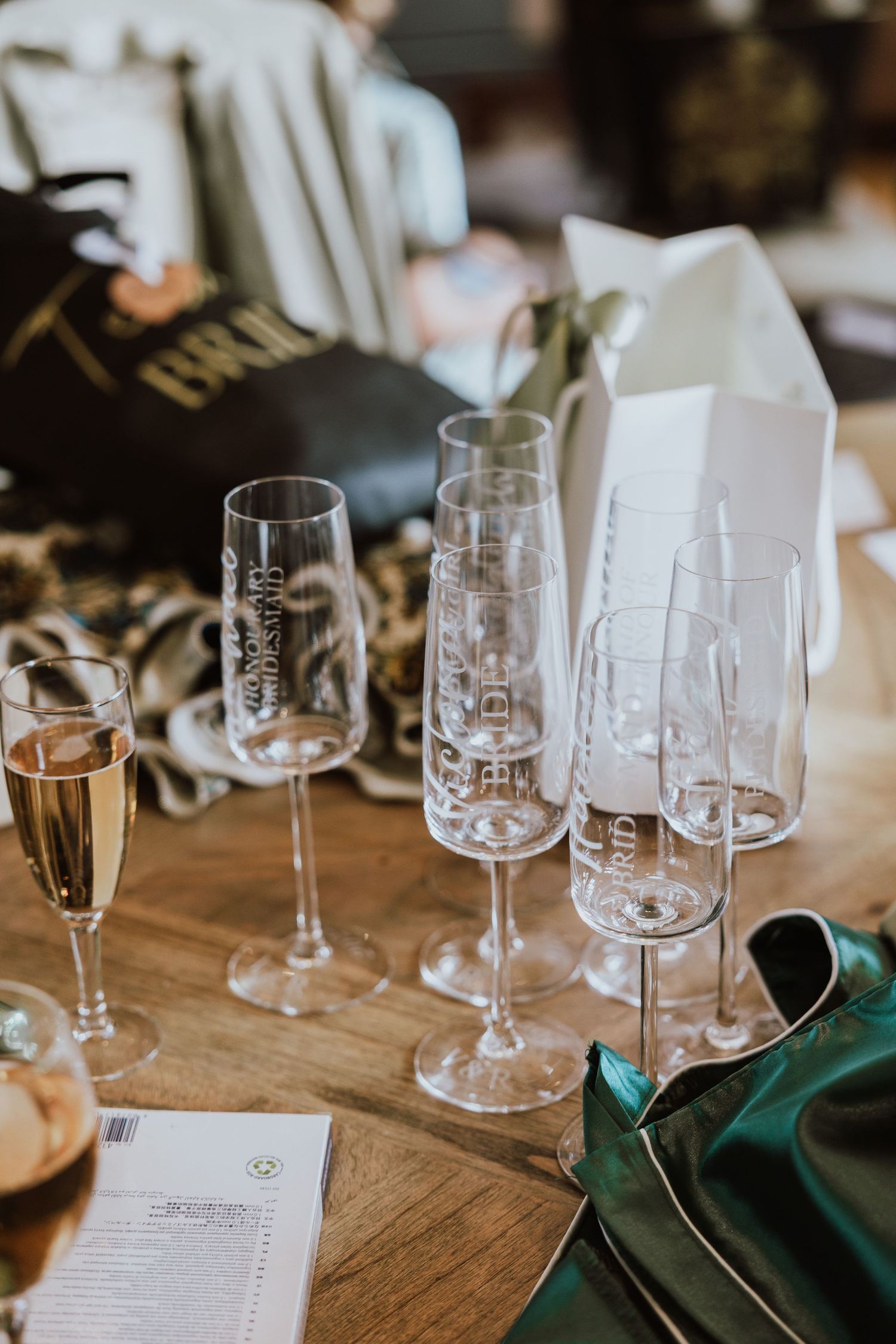 Empty wine glasses and place settings arranged on a rustic wooden table with emerald green napkins.