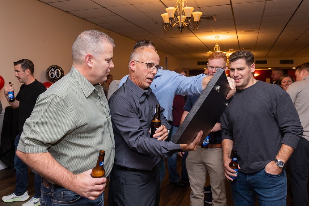 People examine a decorative wooden piece during a social gathering indoors.