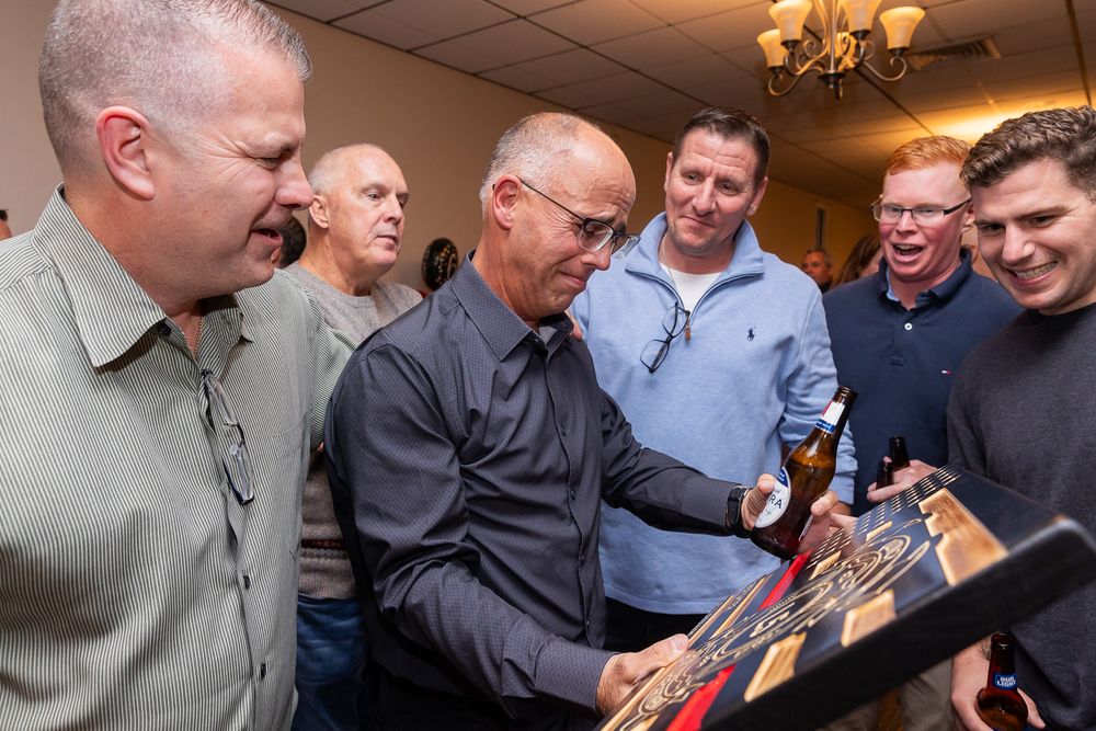 Guests gathered around looking at something during an indoor celebration event.