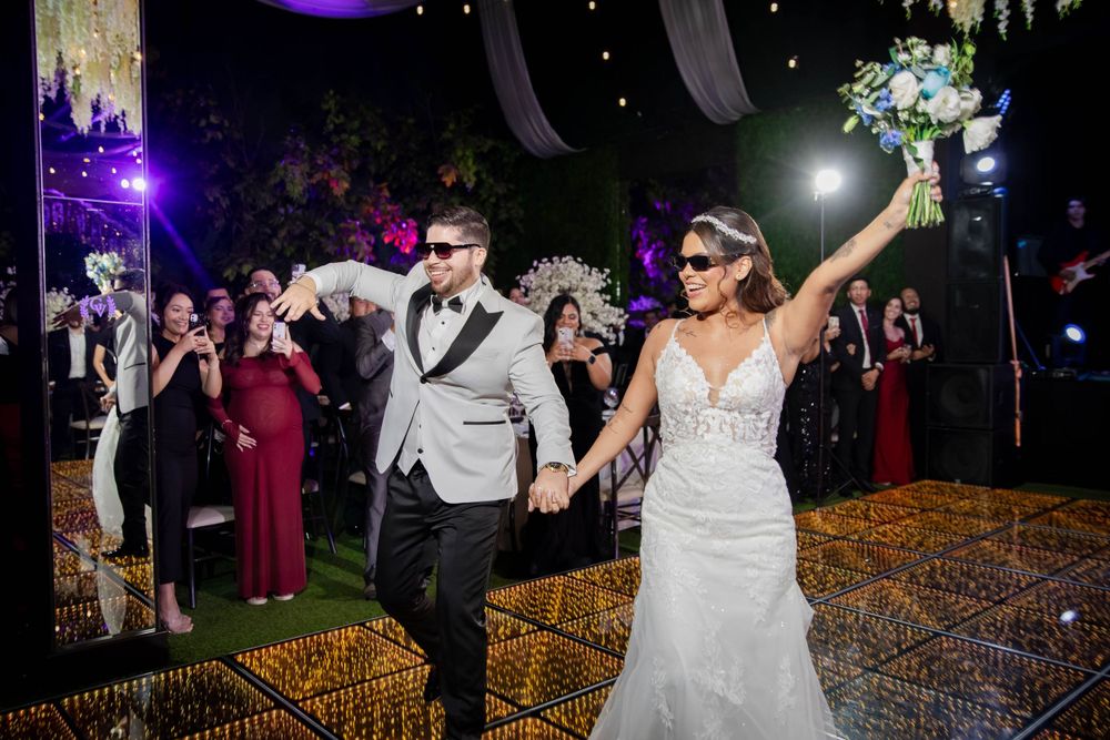 Wedding couple celebrating with guests on illuminated dance floor as they exit their reception.