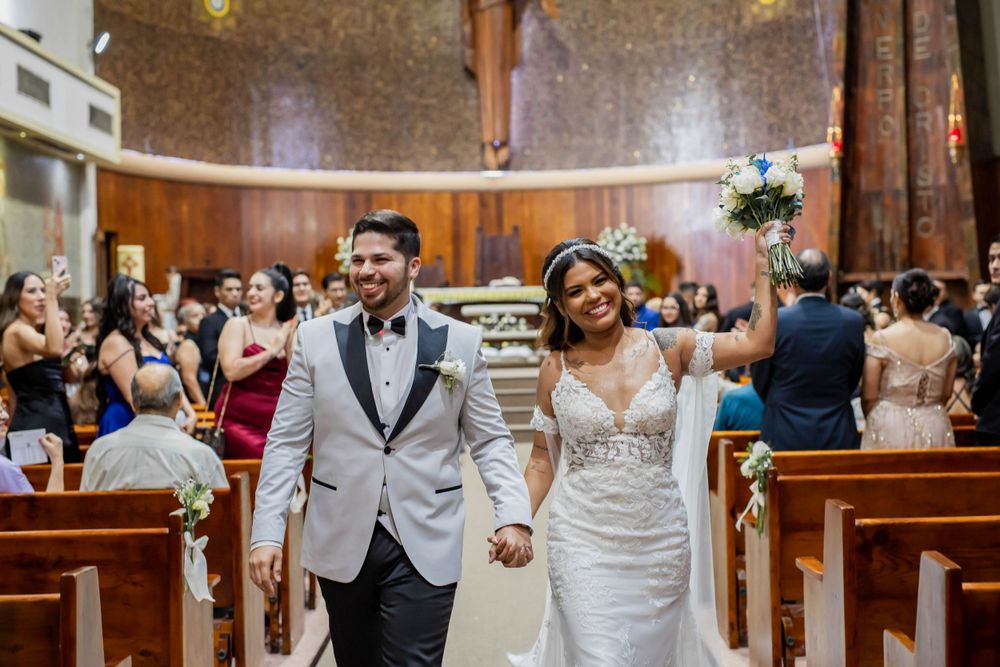 Joyful celebration in church with guests cheering during wedding ceremony.