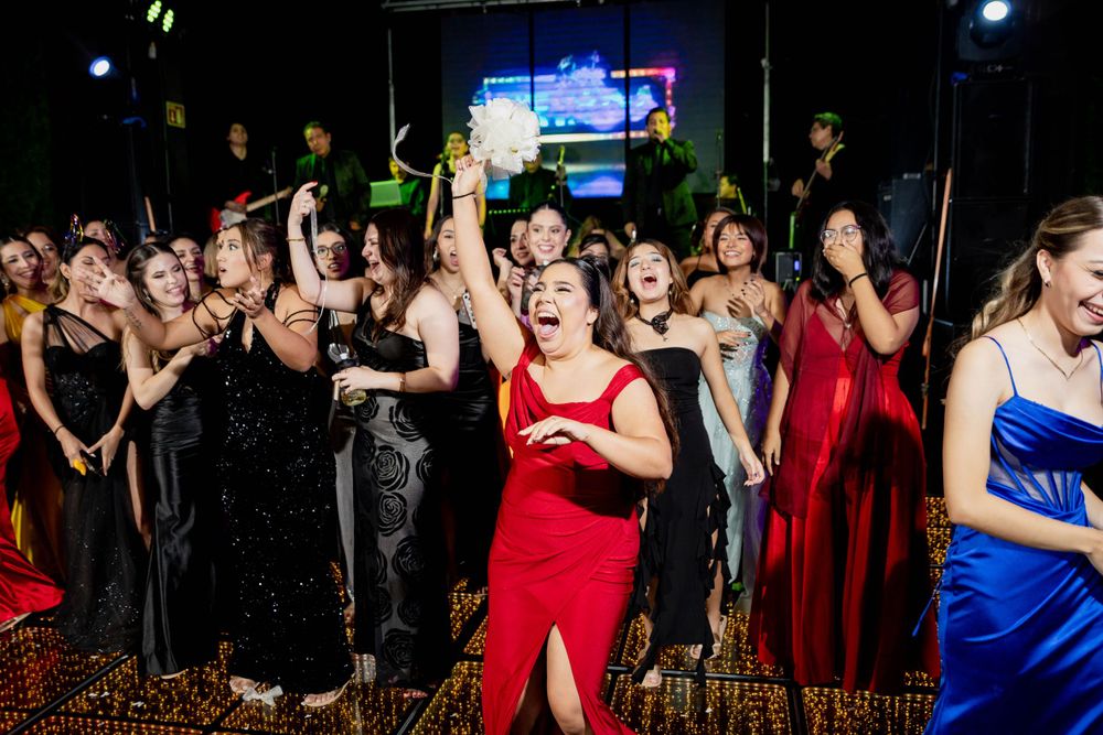 Wedding reception crowd dancing in formal attire under colorful party lights.