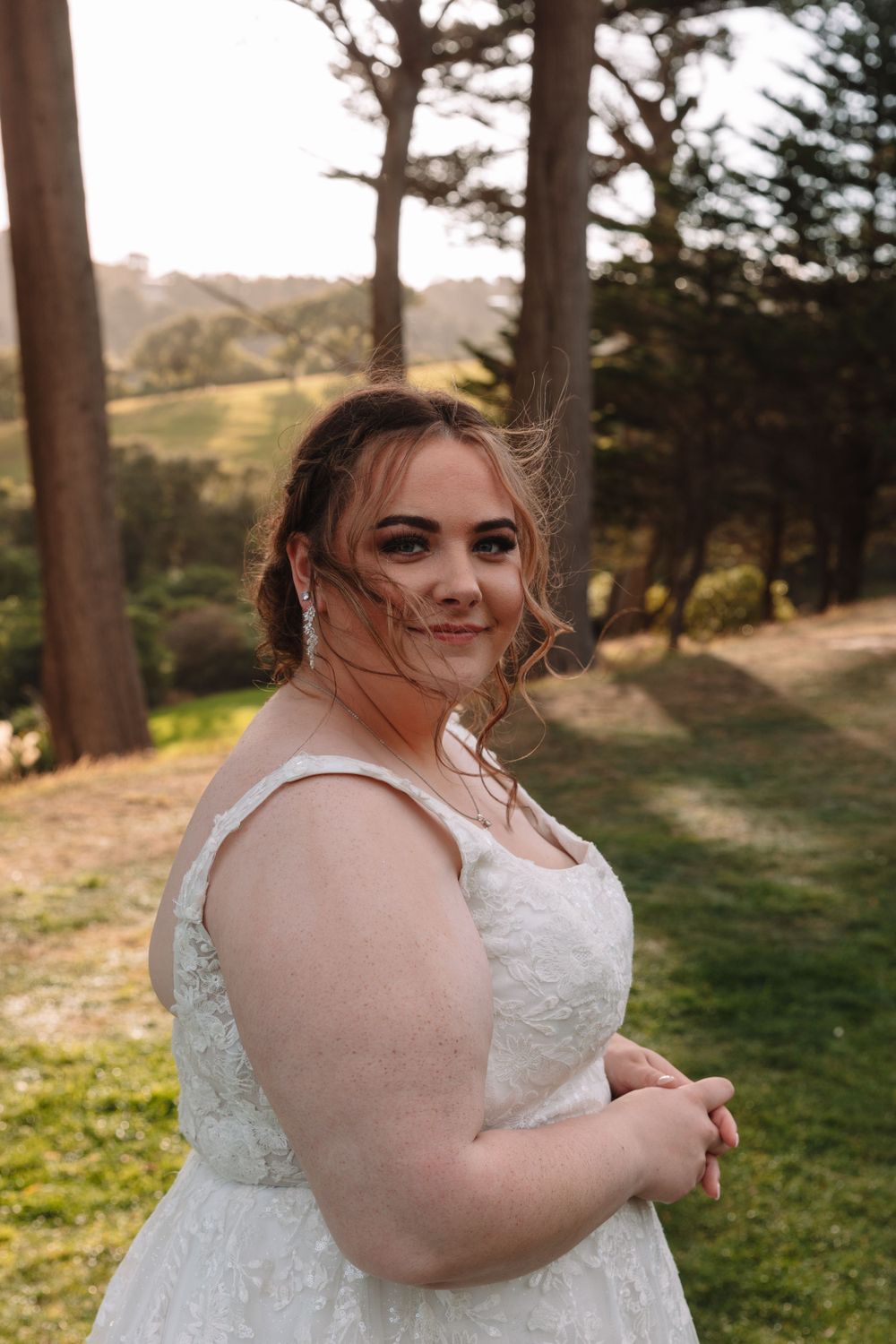 Wedding portrait in natural setting with pine trees and rolling hills in background.