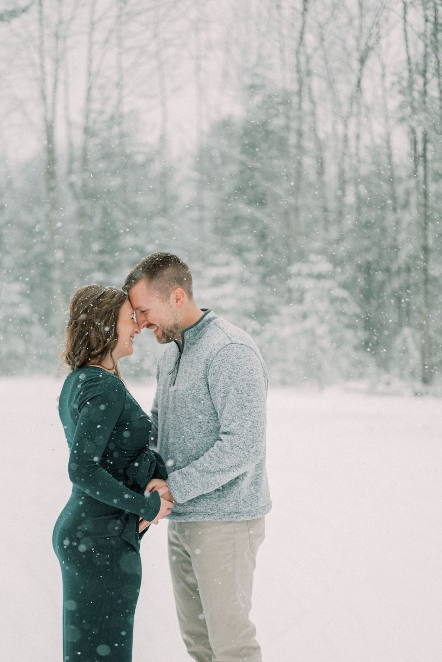An intimate winter maternity moment captured in falling snow.