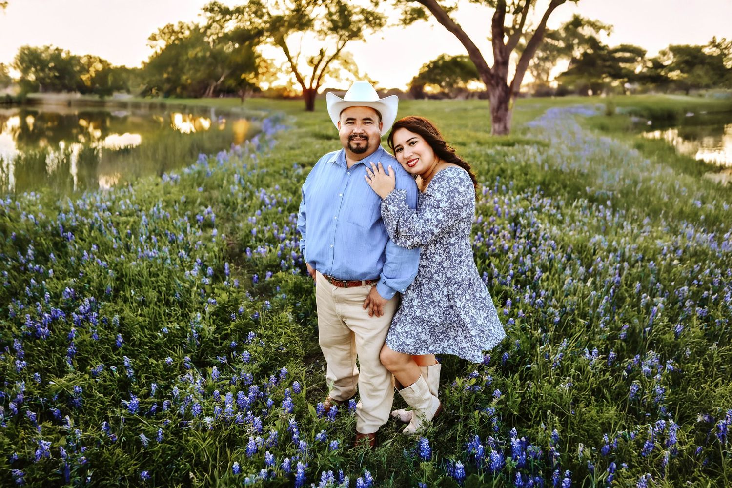 Bride-to-be twirling in a flowy dress surrounded by blooming bluebonnets with her fiancé watching adoringly