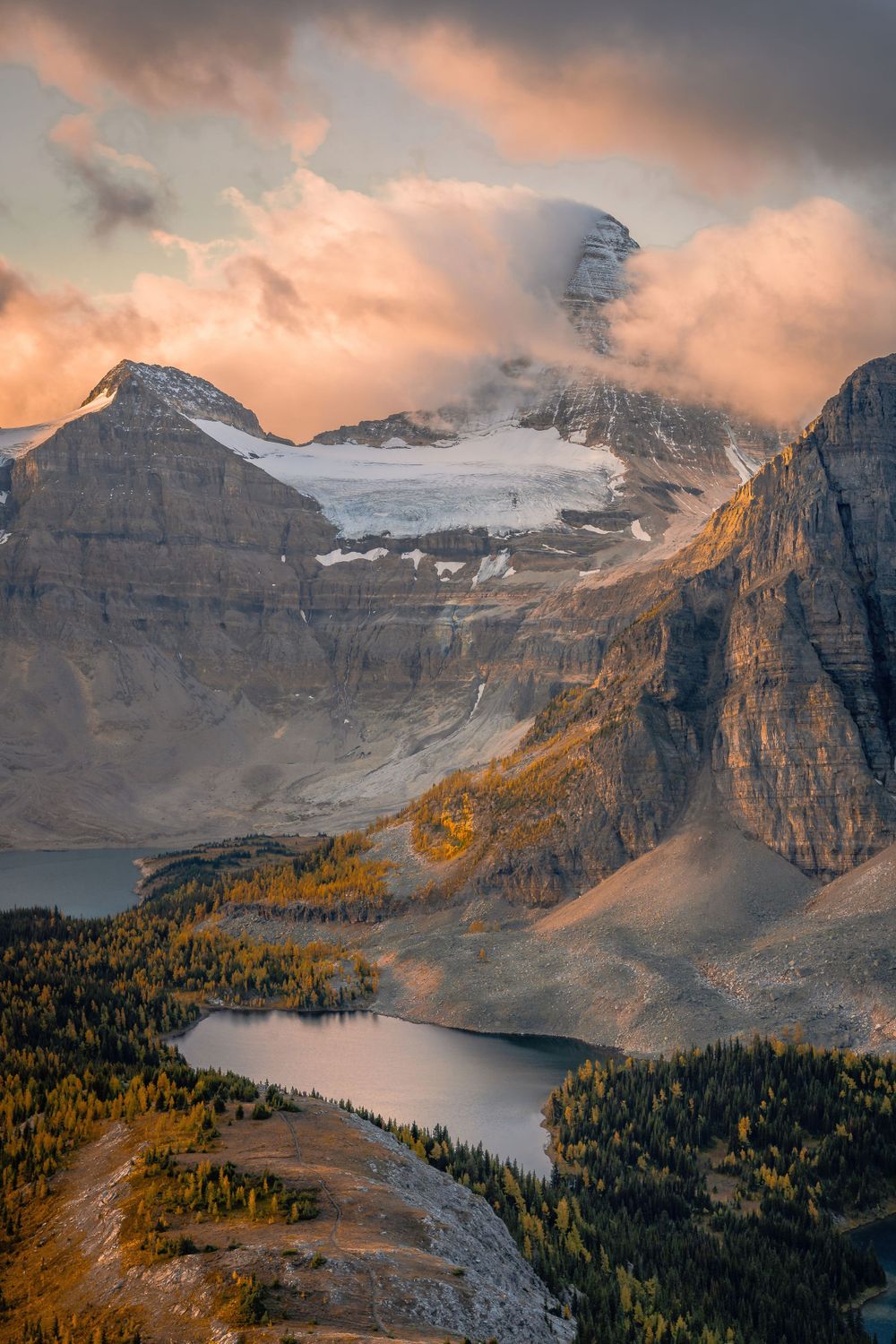 Dramatic mountain landscape with glacial lakes and autumn colors under pink sunset clouds.