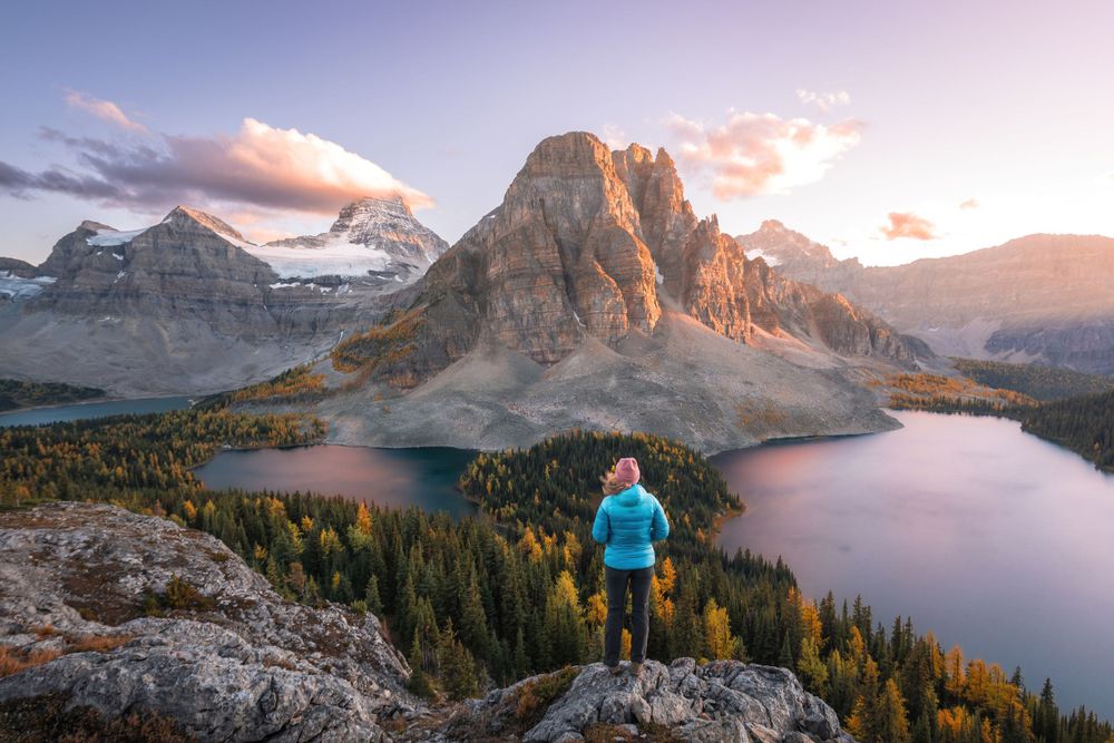 Hiker overlooking mountain lake and peaks during sunset in Canadian Rockies.